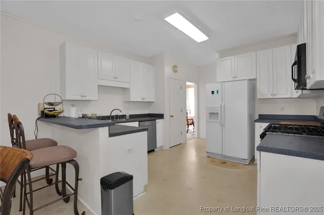 a kitchen with stainless steel appliances granite countertop a refrigerator a sink a stove a dining table and chairs with wooden floor