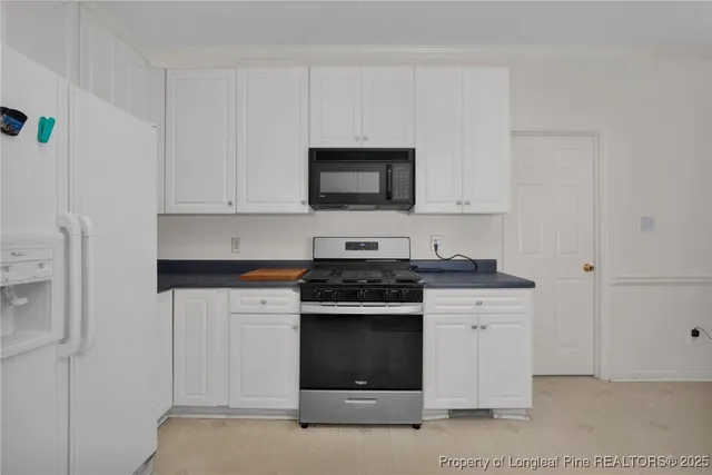 a kitchen with granite countertop white cabinets and stainless steel appliances