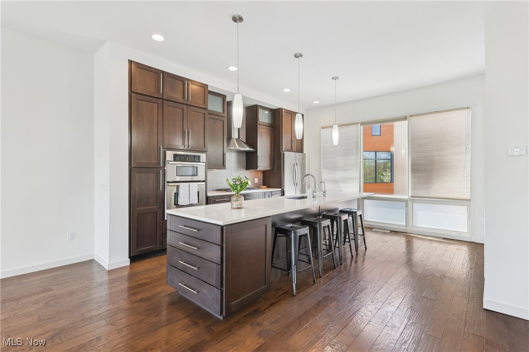 1852 Coltman Road Cleveland, OH 44106 - Photo 10 of 39 Eat-in featuring light countertops, dark wood finished floors, appliances with stainless steel finishes, and wall chimney range hood