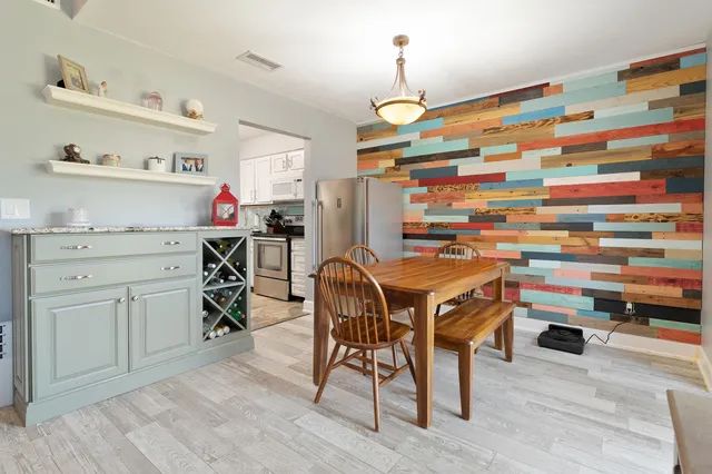 a kitchen with stainless steel appliances kitchen island granite countertop a table chairs in it and wooden floors