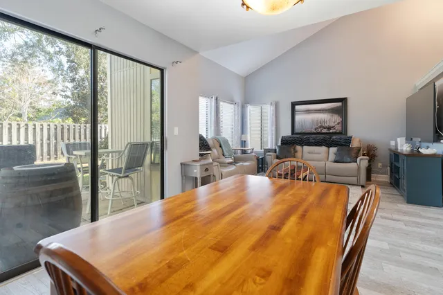 a kitchen with stainless steel appliances granite countertop a dining table chairs refrigerator and a window