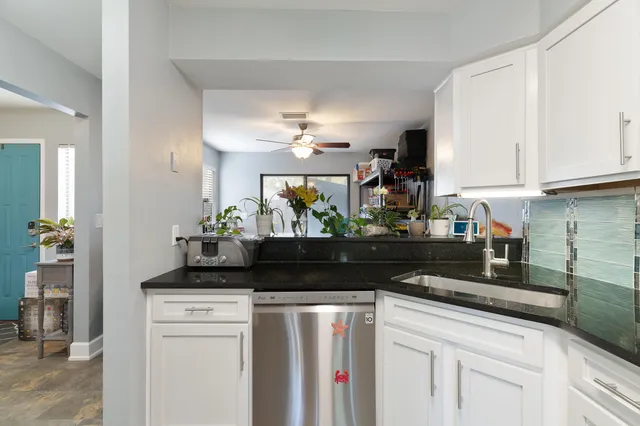 a kitchen with granite countertop a sink dishwasher stove and cabinets