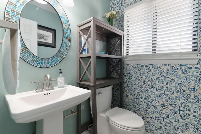 a bathroom with a sink a mirror a toilet and a window