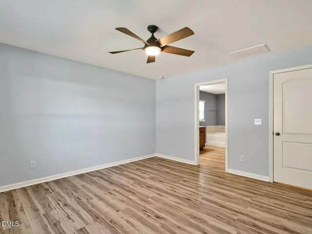 a view of empty room with wooden floor and ceiling fan