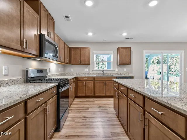 a kitchen with stainless steel appliances granite countertop sink stove microwave and cabinets