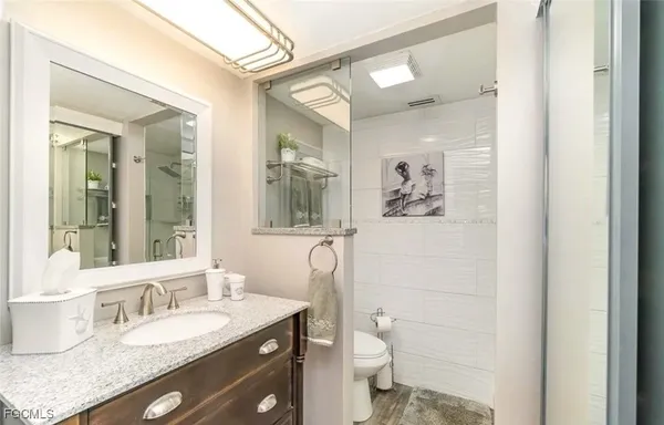 a bathroom with a granite countertop toilet a sink and mirror
