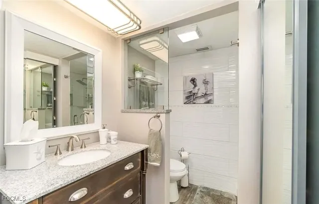 a bathroom with a granite countertop toilet a sink and mirror