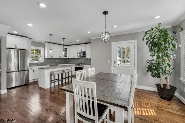 a kitchen with stainless steel appliances a dining table chairs and wooden floor