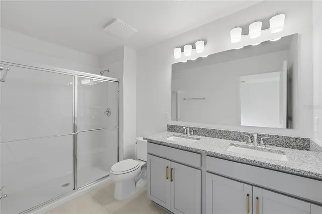 a bathroom with a granite countertop sink a toilet and a mirror