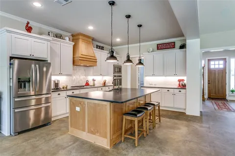 a kitchen with stainless steel appliances kitchen island granite countertop a sink and refrigerator