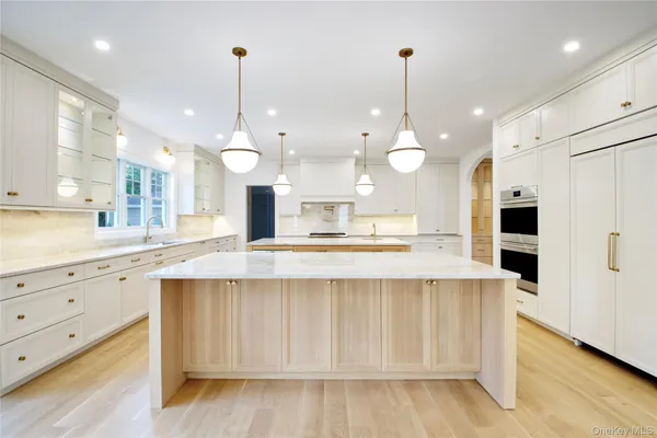 a large kitchen with cabinets a sink a center island and stainless steel appliances