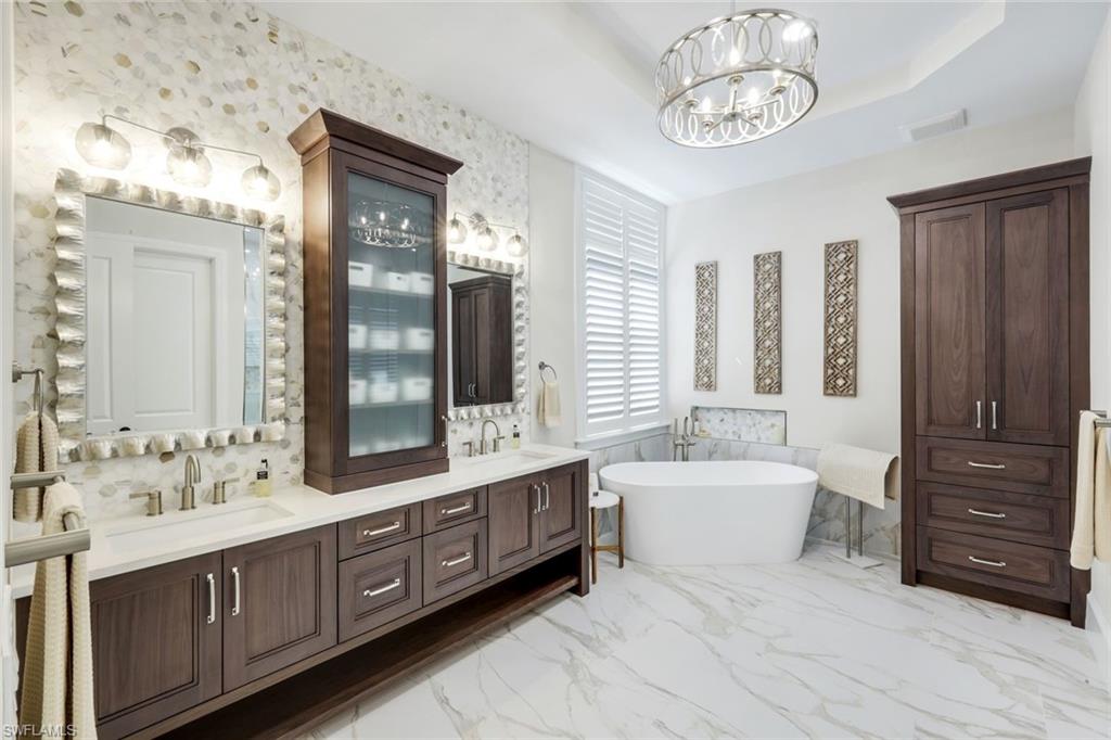 2106 Modena Court Naples, FL 34105 - Photo 23 of 42 a spacious en suite bathroom with a double vanity sink a large mirror and a bathtub