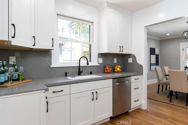 a kitchen with stainless steel appliances white cabinets a sink a stove and a window
