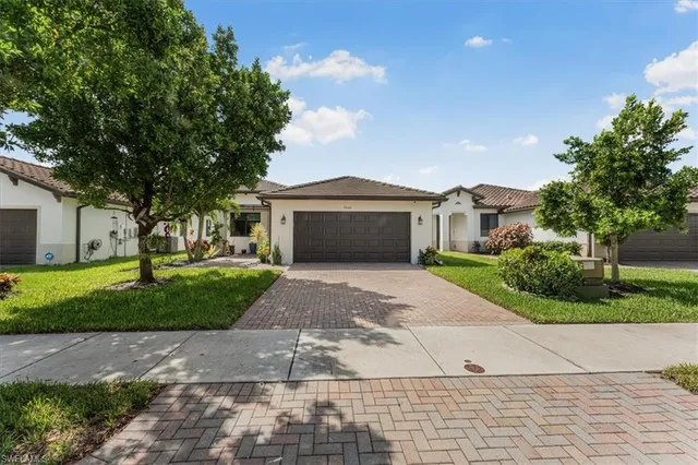 a front view of a house with a garden and trees