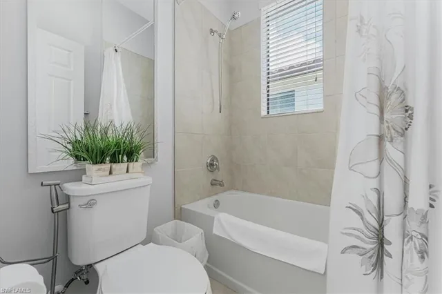 a bathroom with a sink a toilet a window and shower