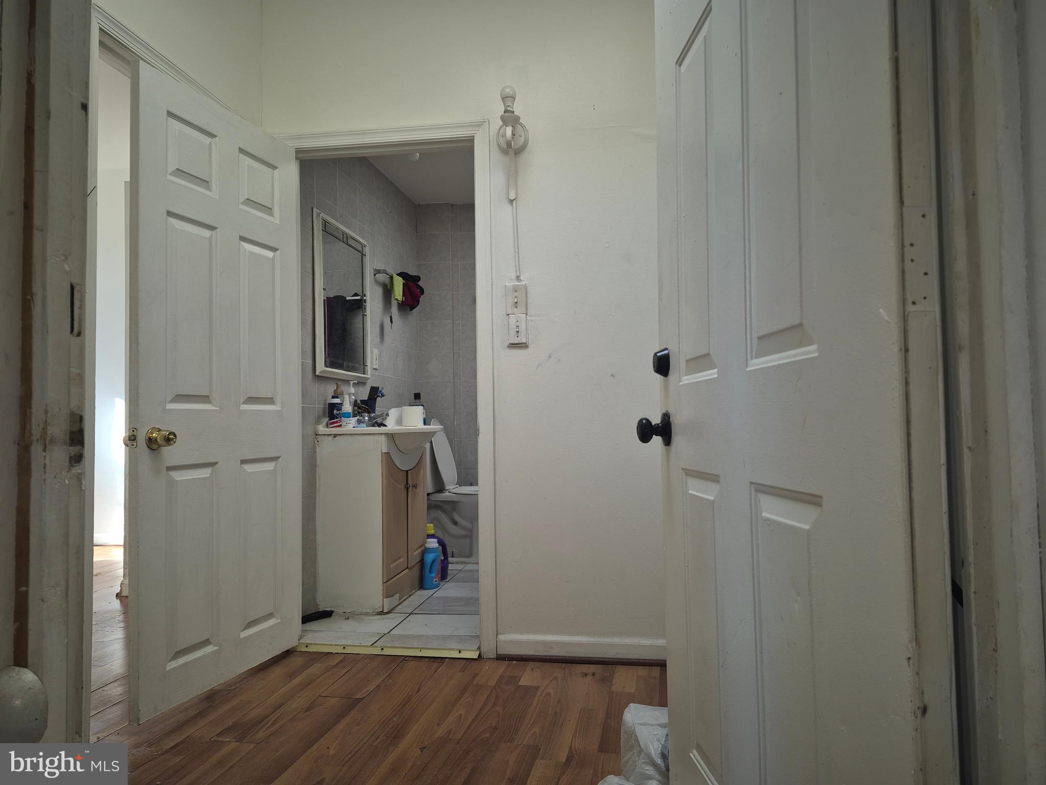 2924 Presstman Street Baltimore, MD 21216 - Photo 4 of 13 a view of a hallway with wooden floor and a bathroom