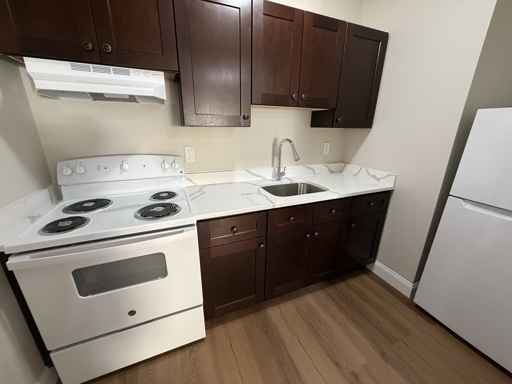 39 Newhall Street, Unit 20 Lynn, MA 01902 - Photo 2 of 11 a kitchen with a stove a sink and a refrigerator with wooden floor