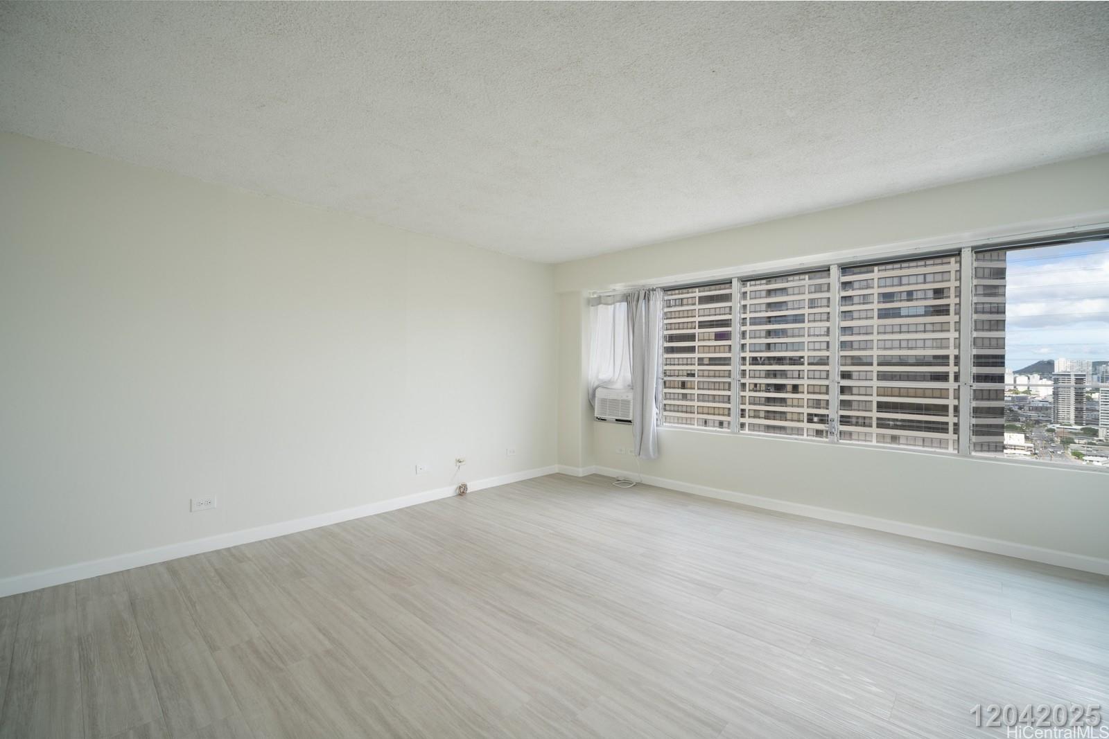 2525 Date Street, Unit 2405 Honolulu, HI 96826 - Photo 5 of 14 an empty room with wooden floor and windows