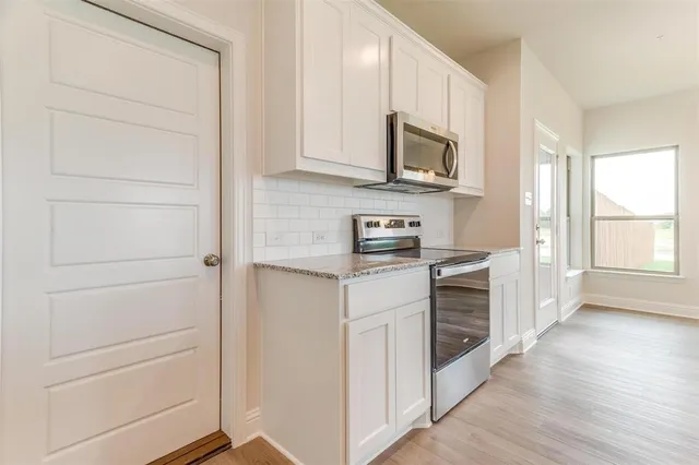 a kitchen with stainless steel appliances white cabinets and a wooden floor