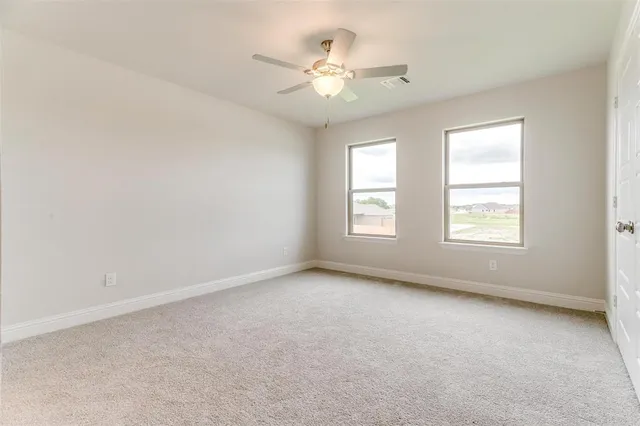 an empty room with windows and ceiling fan