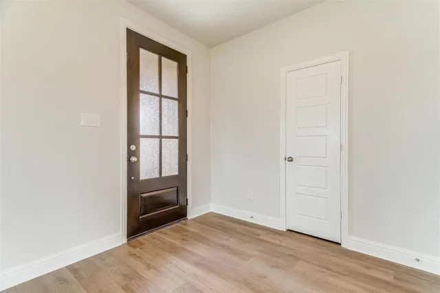 an empty room with wooden floor cabinet and windows