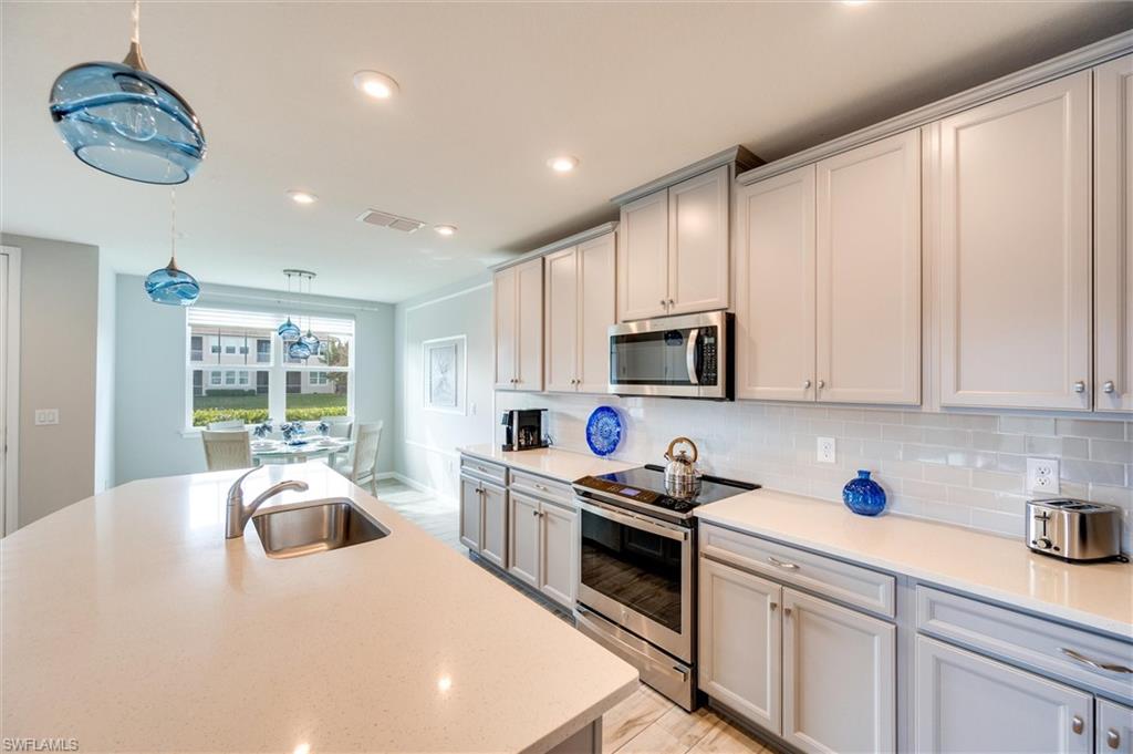 4607 Arboretum Circle, Unit 103 Naples, FL 34112 - Photo 6 of 29 a kitchen with stainless steel appliances granite countertop a sink a stove and a refrigerator