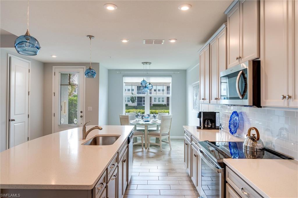 4607 Arboretum Circle, Unit 103 Naples, FL 34112 - Photo 7 of 29 a open kitchen with stainless steel appliances granite countertop a sink a stove and a refrigerator with wooden floor