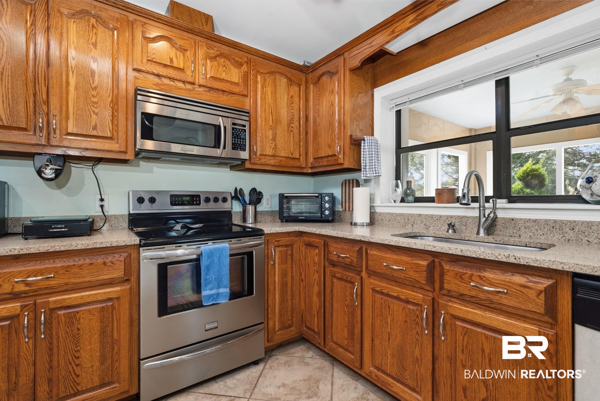 15025 Bellingrath Road Coden, AL 36523 - Photo 45 of 79 Kitchen featuring stainless steel appliances, wood finish cabinets, light stone countertops, and light tile patterned flooring