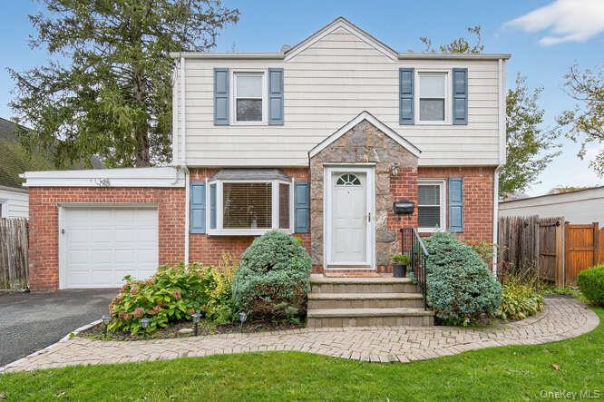453 Andrews Road Mineola, NY 11501 - Photo 1 of 1 Colonial house featuring an attached garage, asphalt driveway, and brick siding