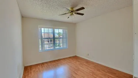 an empty room with a window and a fan
