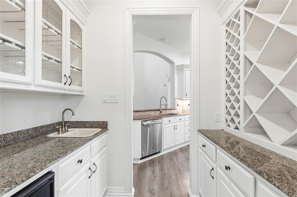 967 East Bethel School Road Coppell, TX 75019 - Photo 11 of 39 Wet bar featuring white cabinetry, granite countertops, an undermount sink, and a built-in wine rack