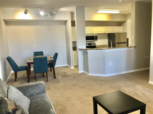 a living room with furniture and a dining table with kitchen view