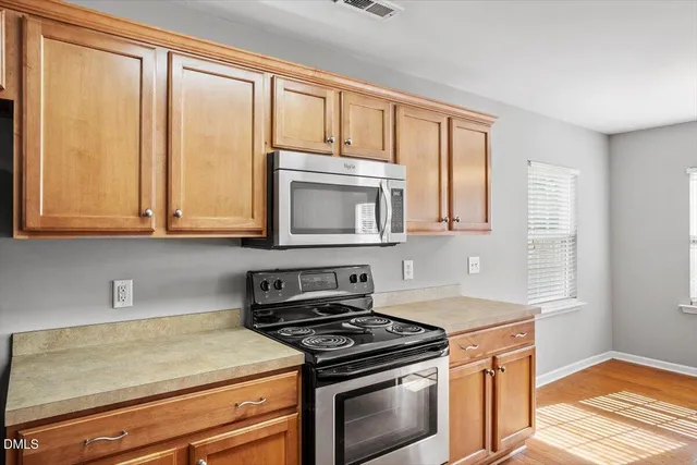 a kitchen with stainless steel appliances granite countertop a sink a stove cabinets and wooden floor