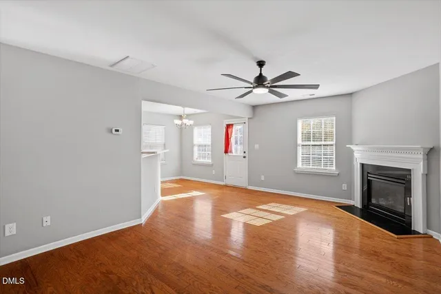 a view of a livingroom with a ceiling fan a fireplace and wooden floor