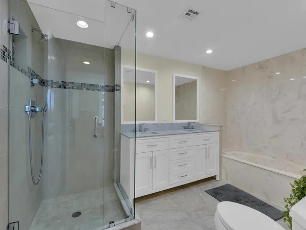 a bathroom with a shower sink vanity mirror and toilet