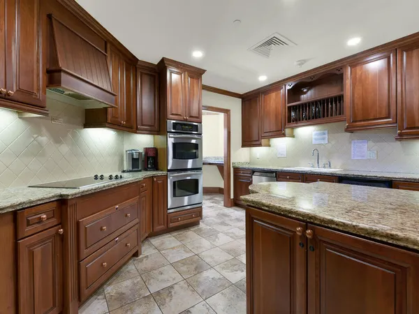 a kitchen with stainless steel appliances granite countertop wooden cabinets a stove a sink and a oven