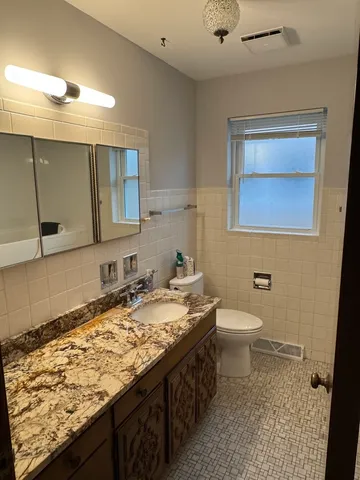 a bathroom with a granite countertop sink and a toilet