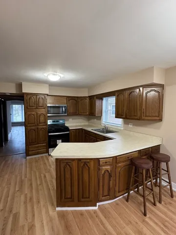 a kitchen with stainless steel appliances a kitchen island hardwood floor sink stove dining table and chairs