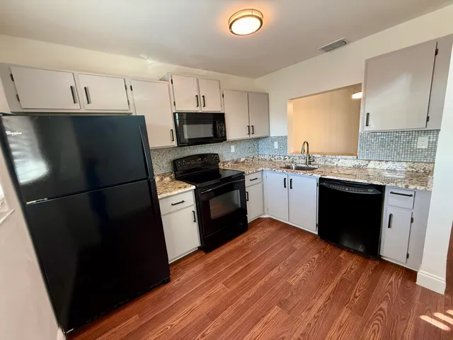 a kitchen with a sink a refrigerator a microwave and cabinets