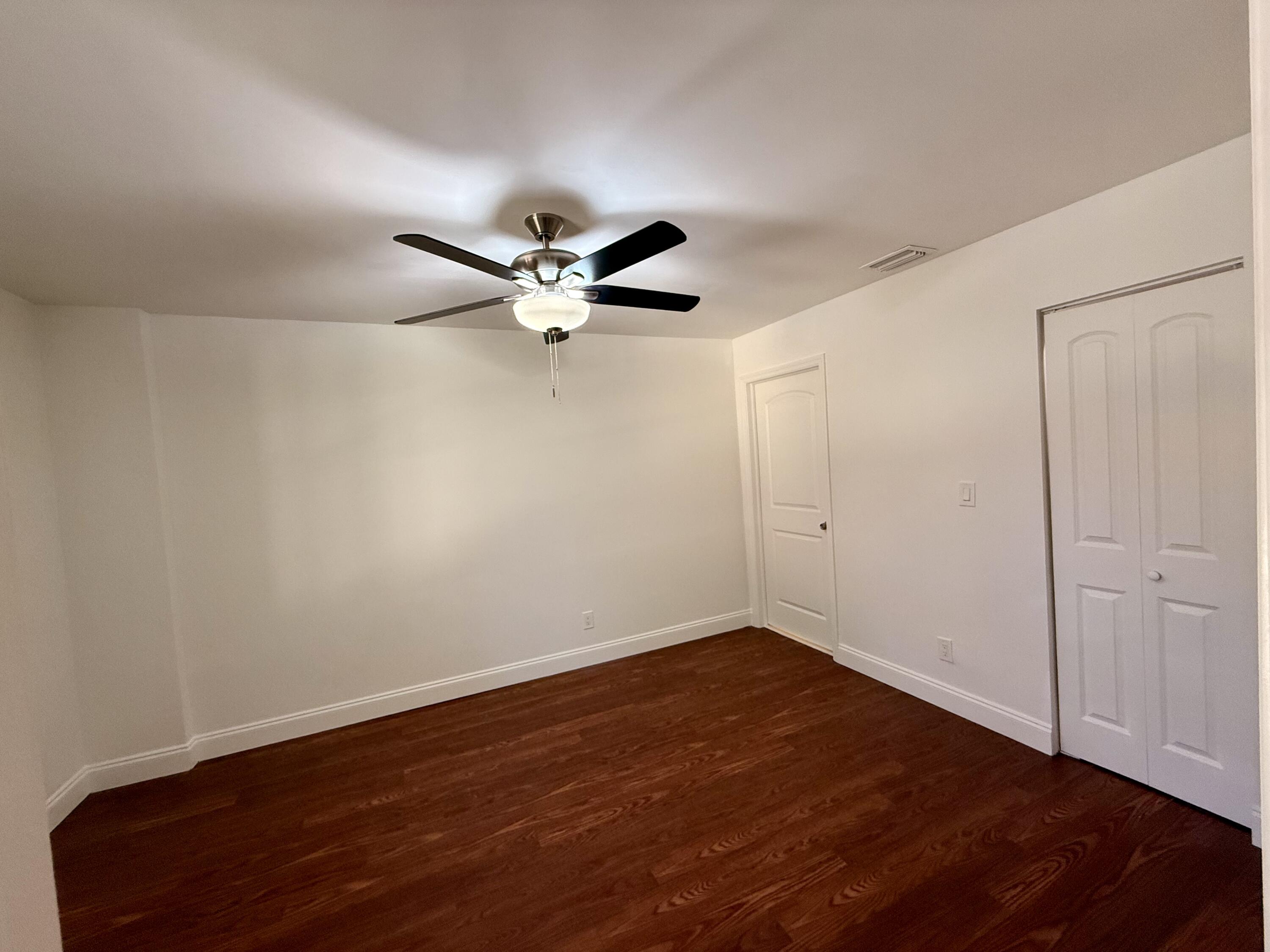 9503 Boca Cove Circle, Unit 610 Boca Raton, FL 33428 - Photo 5 of 16 an empty room with wooden floor fan and windows
