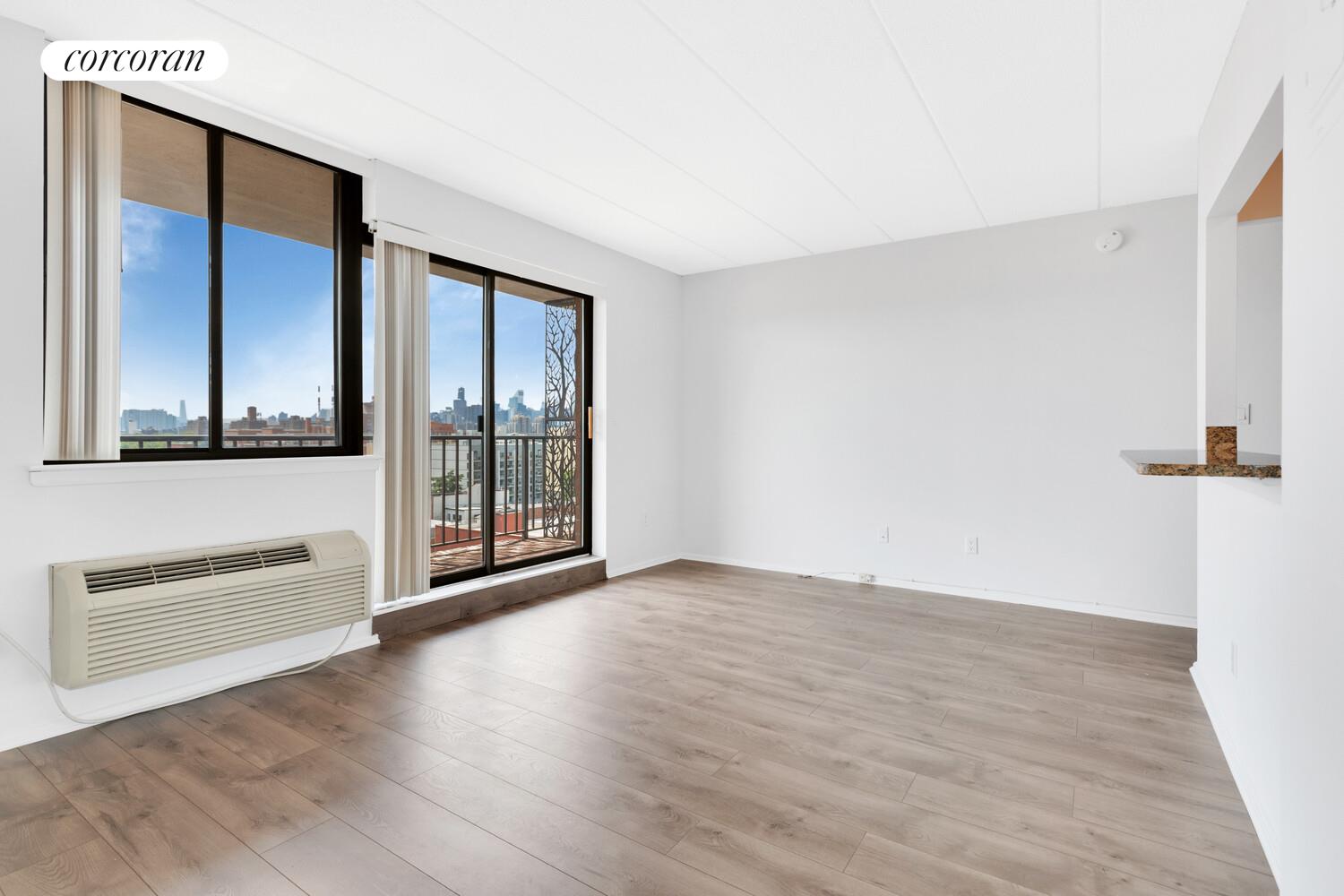 23-22 30th Road, Unit 8G Queens, NY 11102 - Photo 3 of 11 an empty room with wooden floor and windows