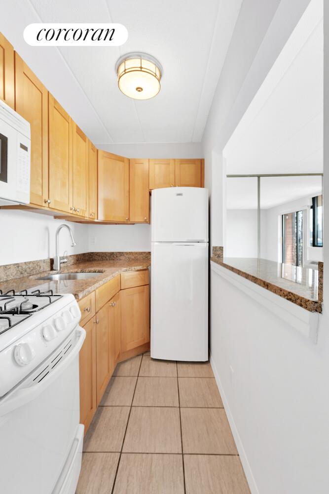 23-22 30th Road, Unit 8G Queens, NY 11102 - Photo 8 of 11 a kitchen with a refrigerator sink stove and cabinets