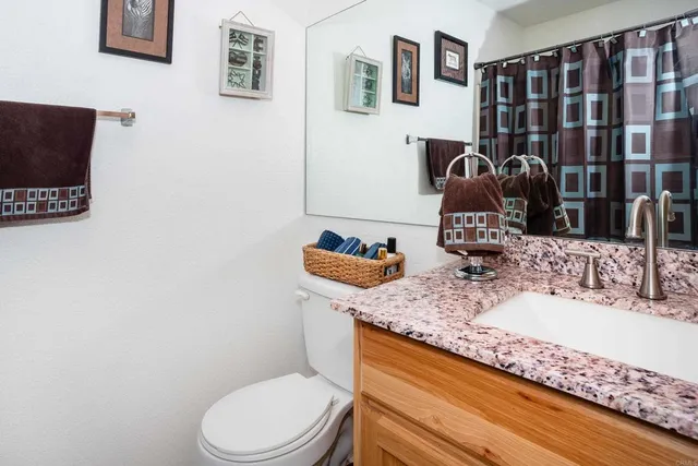 a bathroom with a granite countertop toilet sink and mirror