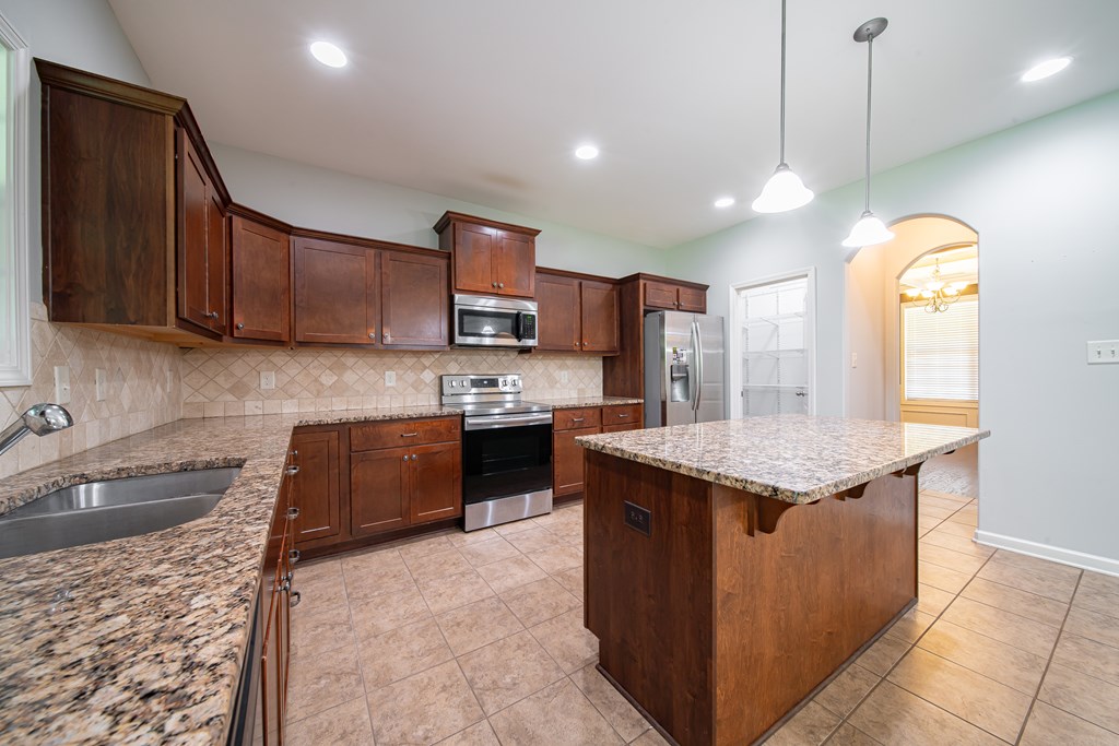 38 Pin Oak Way Hamilton, GA 31811 - Photo 19 of 50 a kitchen with granite countertop kitchen island stainless steel appliances a sink a counter top space cabinets and wooden floor
