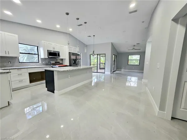 a large white kitchen with stainless steel appliances granite countertop lots of counter top space