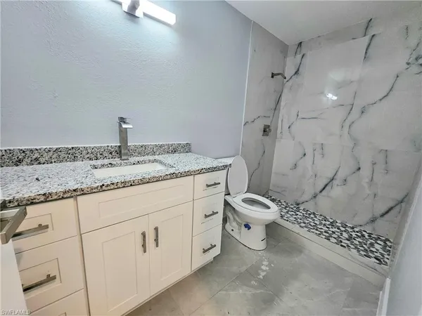 a bathroom with a granite countertop sink a toilet and shower