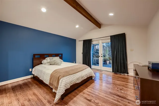 a bedroom with a large bed and wooden floor