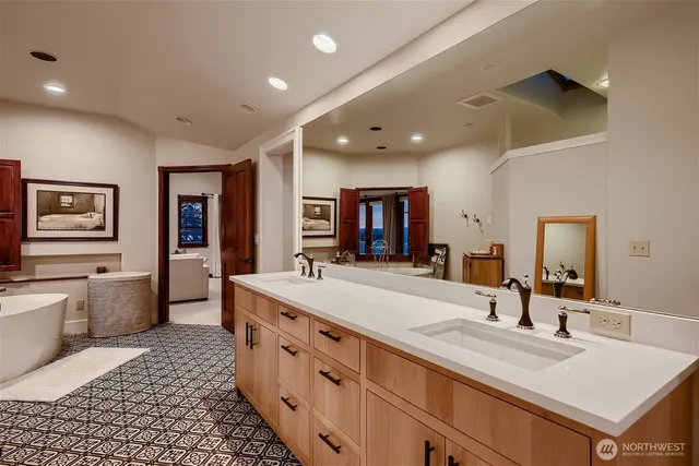 a bathroom with a double vanity sink mirror and bathtub