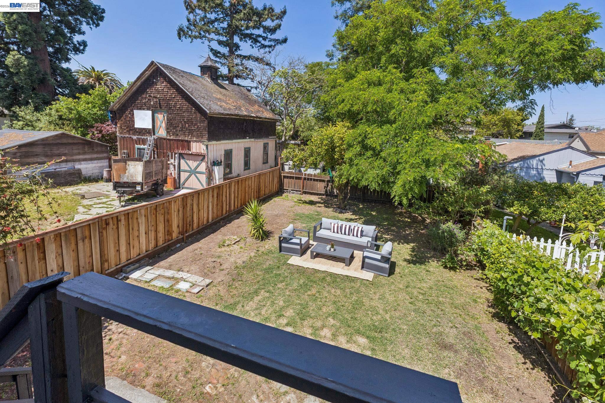 1219 Pearl Street Alameda, CA 94501 - Photo 34 of 40 a wooden bench sitting in backside of a house with large trees and wooden fence