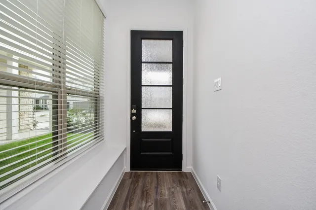 a view of a hallway with wooden floor and a bathroom